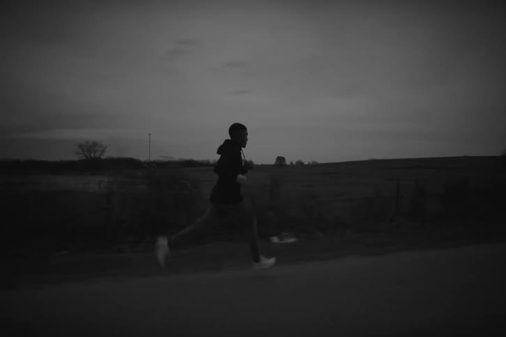 Man running along the road next to natural fields