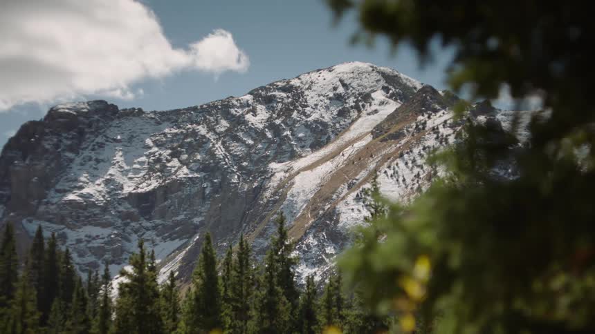 A mountain with a snowcovered peak stands against a blue sky