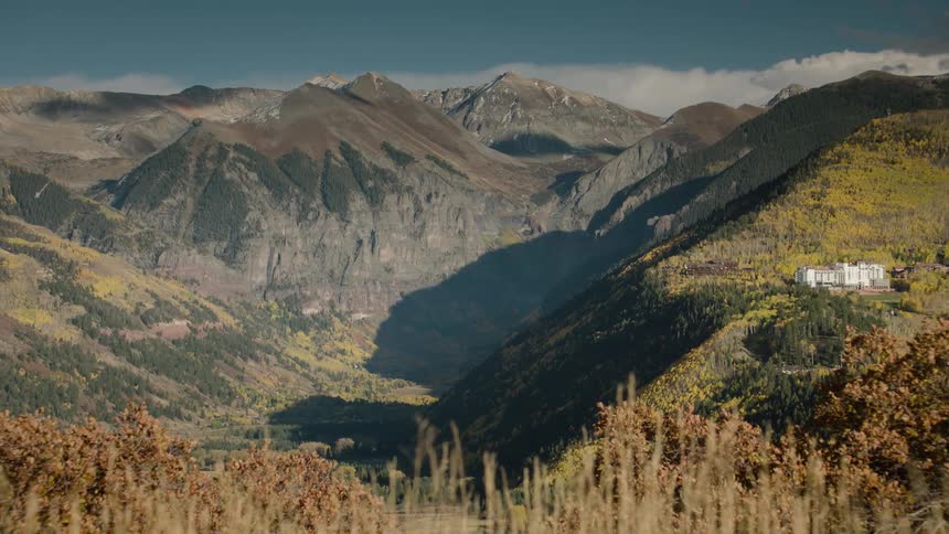 A valley surrounded by forests and mountains under a clear sky