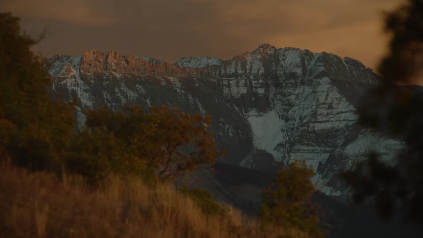 Natural landscape of trees and mountains in the background with snow and a red sky