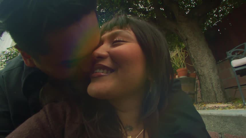 Man kisses woman on the cheek while she smiles at him
