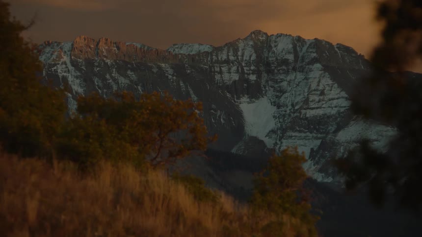 Natural landscape of hills and mountains with snow and a reddish sky at dawn