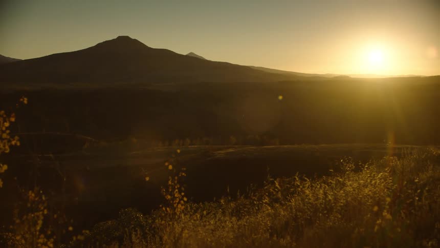 Landscape of sunrise on the horizon over the silhouette of a mountain and hills