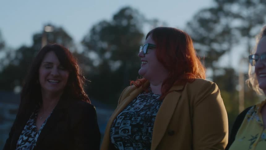 Three female friends walking outdoors talking and smiling