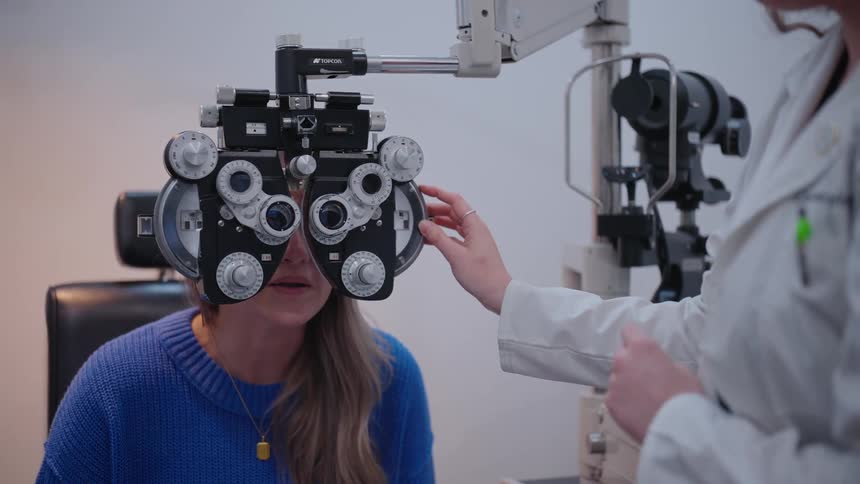 Female looking through a phoropter getting her eyes examed