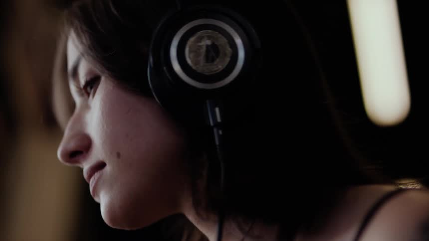 Close up of a woman wearing headphones bobbing her head to music