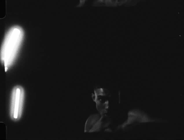 Man in a dimly lit room shirtless throwing boxing punches