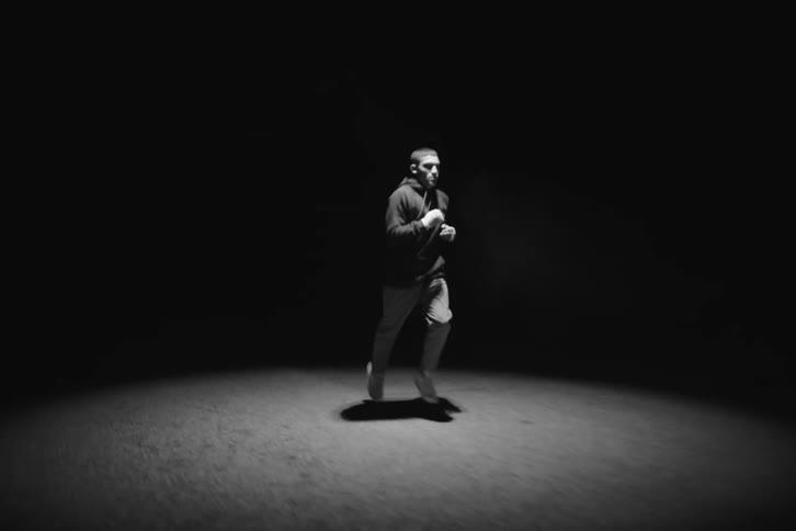 A young man running on a road under a spotlight at night