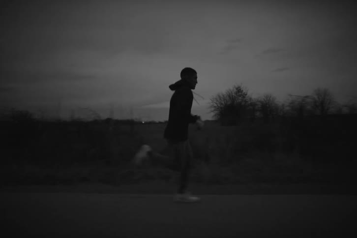 A young man jogging on a road on the countryside