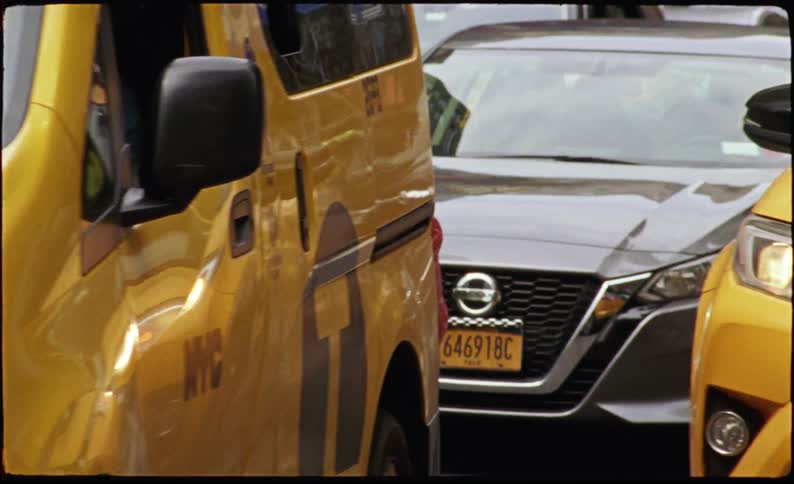 Cars and taxis driving on a busy city street