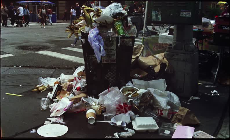 Corner of a metropolis full of trash and pedestrians walking
