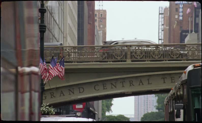 A bridge over a city street with a car passing over it