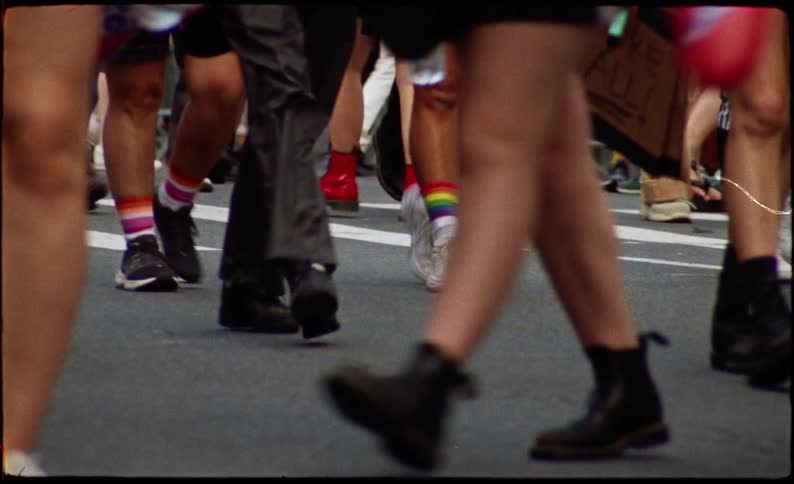 Legs of several people walking on the asphalt with homosexual demonstration posters