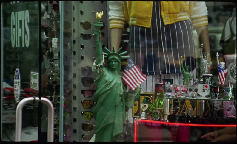 Statue of liberty on display in a store window in a city with pedestrians walking by