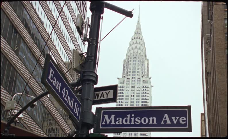 Street of a metropolis with a signpost and skyscrapers around on a cloudy day
