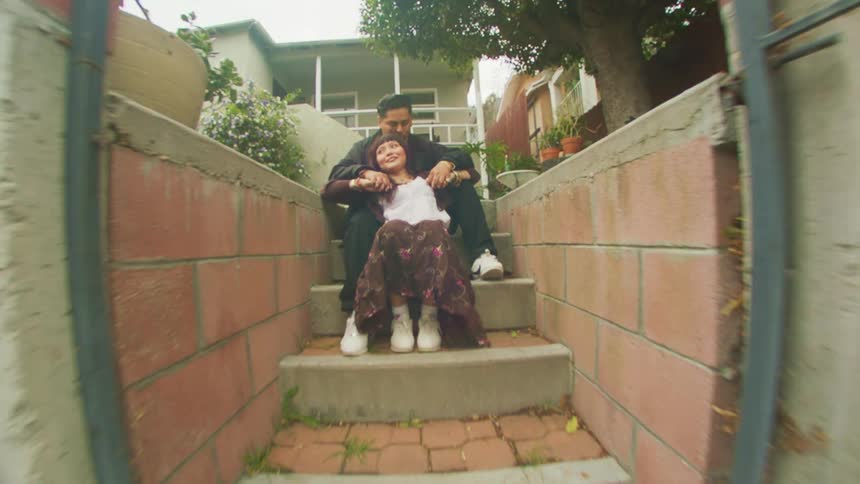 A young couple sitting on outdoor steps past a metal gate