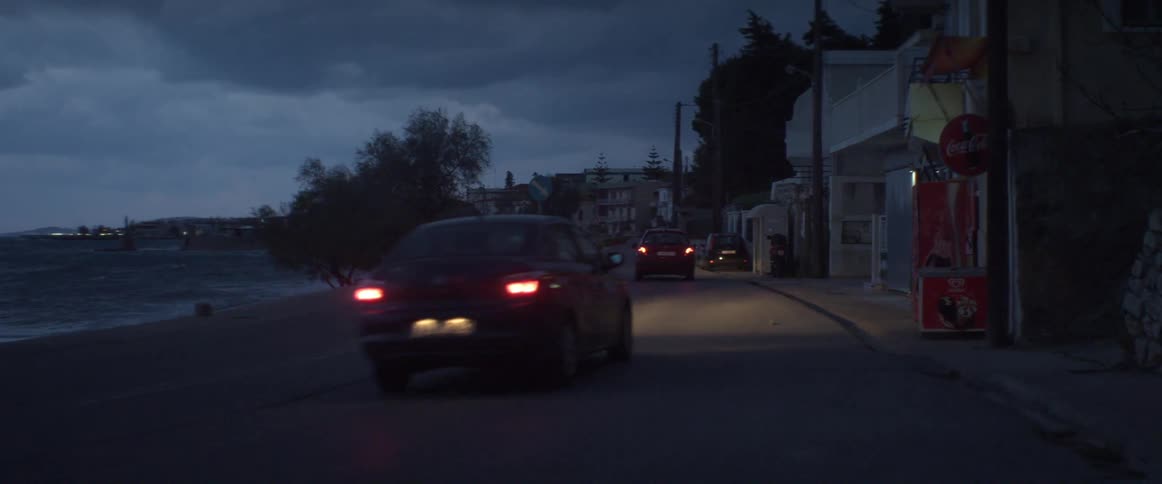 Two red cars driving down a dark street