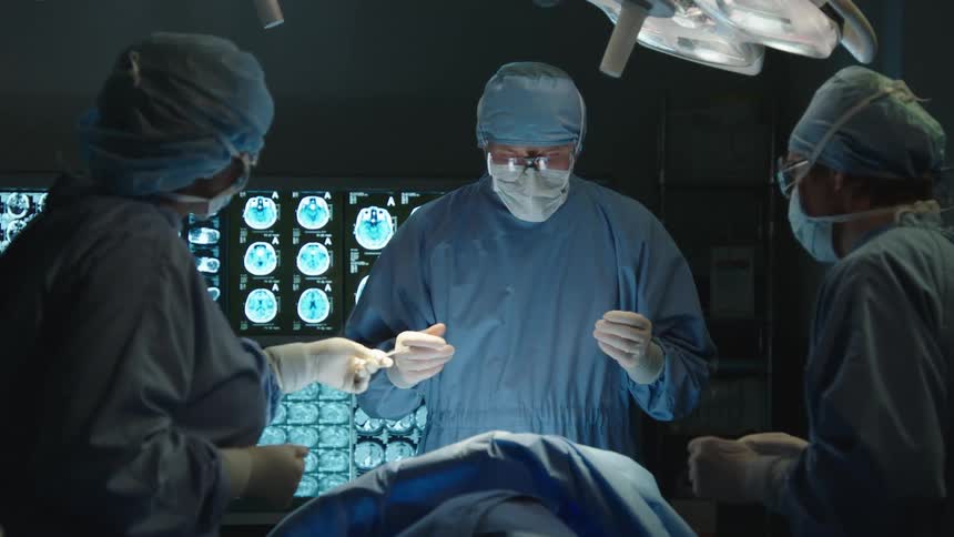 Surgeon and his team picking up a scalpel while standing in a surgical room as a patient