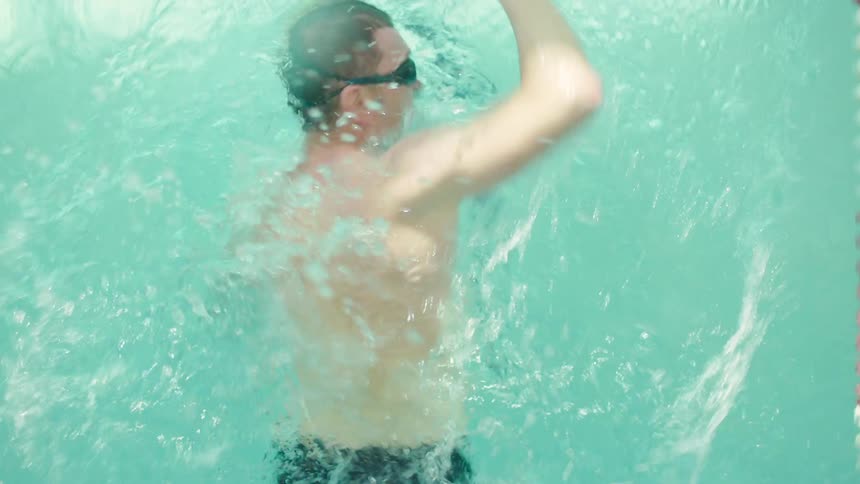 A man swims laps in a large indoor swimming pool