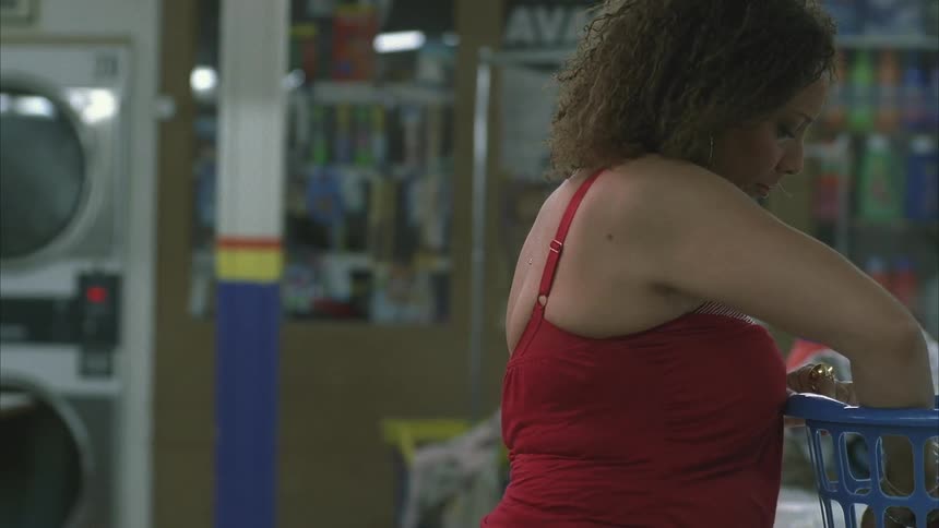 A woman arranging clothes on a basket in a laundromat