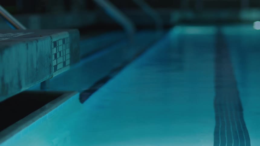 Corner of a swimming pool with transparent waters illuminated at night in an indoor environment
