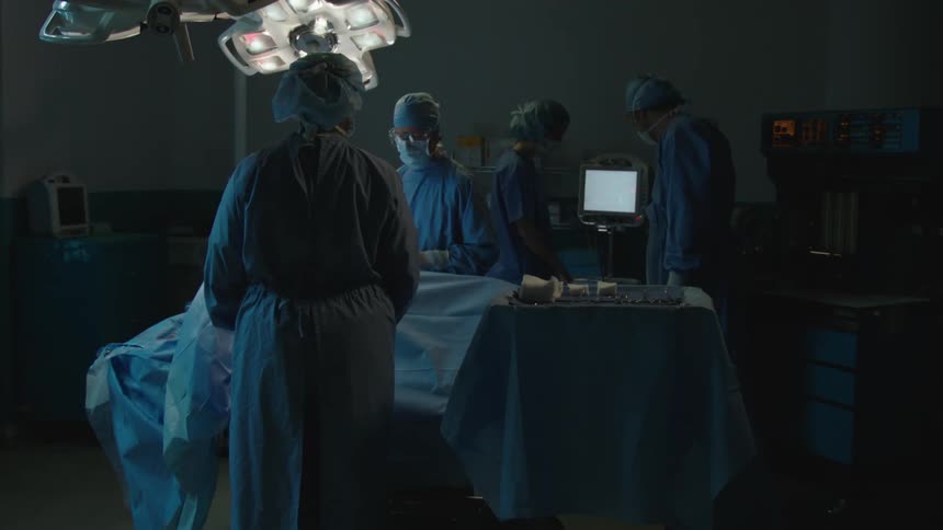 Medical team made up of surgeons in a dimly lit operating room