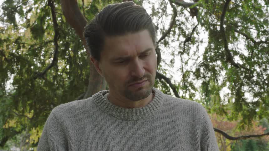 Portrait of a man with a distrustful facial expression standing in a forest