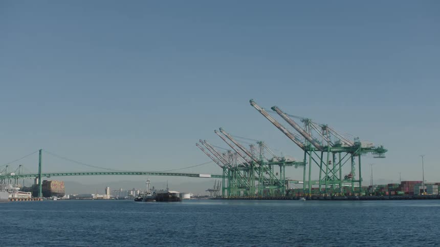 Panorama of the sea with cranes in a logistics distribution center and a bridge in the background