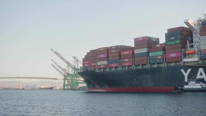 A tugboat escorts the yang ming cargo ship as it delivers freight