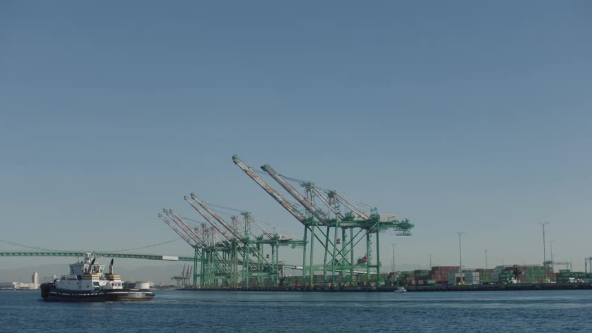 Large boat cruises past loading dock near suspension bridge