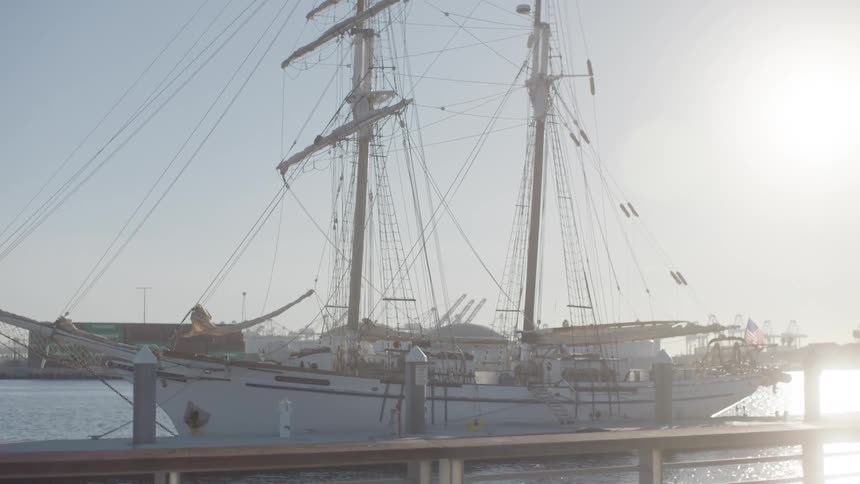 A large fishing boat with several ropes and it is on top of the water on a pier