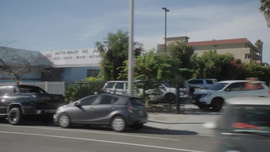 City street with vehicle traffic and intersections with commercial buildings
