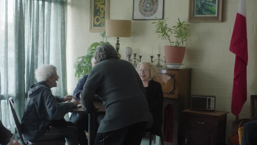 Elderly women and men are sitting at a table laughing heartily