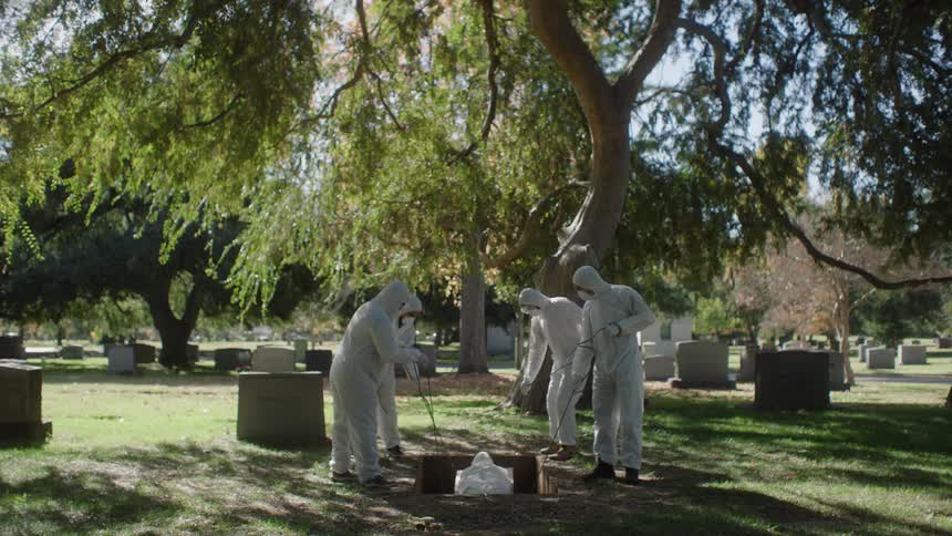 Four workers bury a corpse in a cemetery