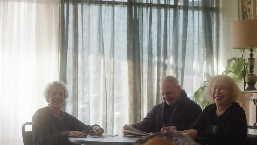 Man and two ladies sitting at a table laughing