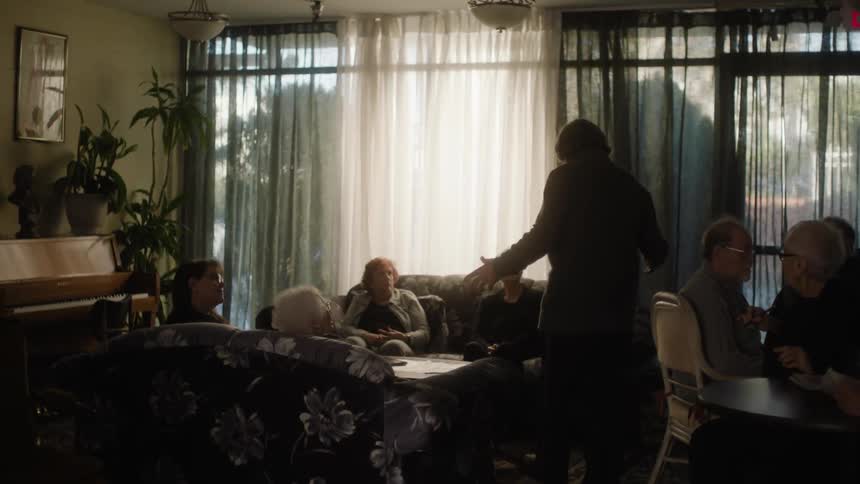 Senior citizens sit at tables and talk to each other at nursing home