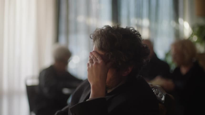 A man sitting in an office rubbing his head