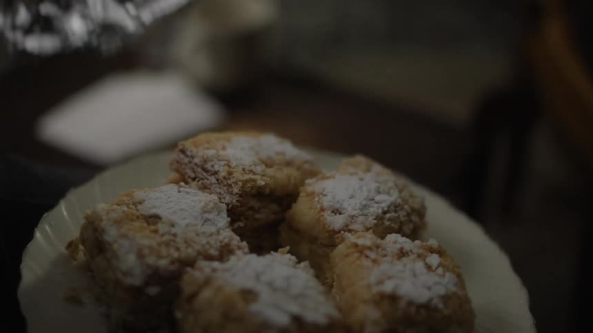 A man removes the tinfoil from a plate of pastries and hands them to someone
