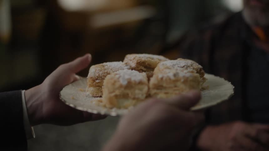 A human hand takes a plate with several pieces of stuffed bread and offers it to a person