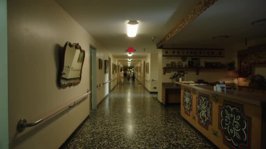 Man in a suit passing by and other people in the background walking in a hallway