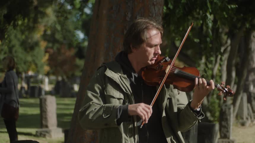 A man playing violin at a cemetery