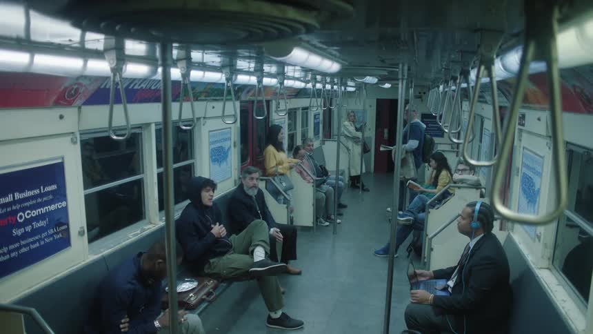 People listen to a man sitting on seats while traveling by subway