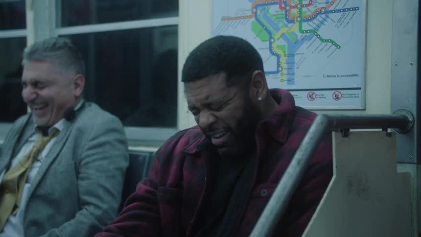 Two men sitting on the bench of a moving train laughing