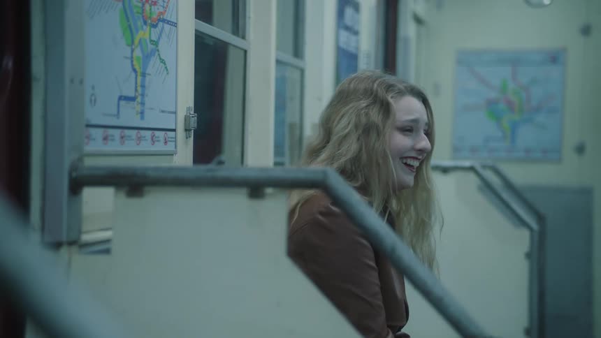 A blonde woman laughs while riding a subway