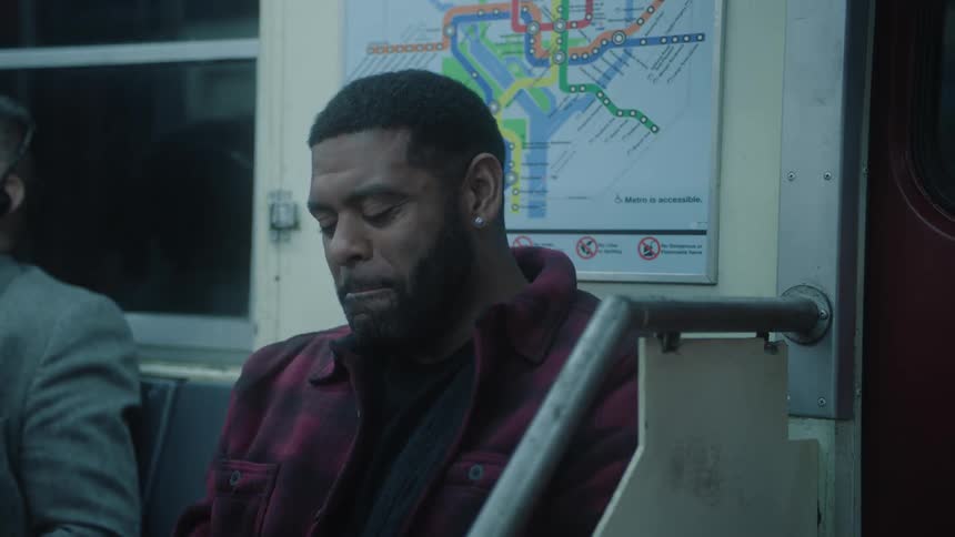 A man is sitting on a subway seat and starts laughing his head off