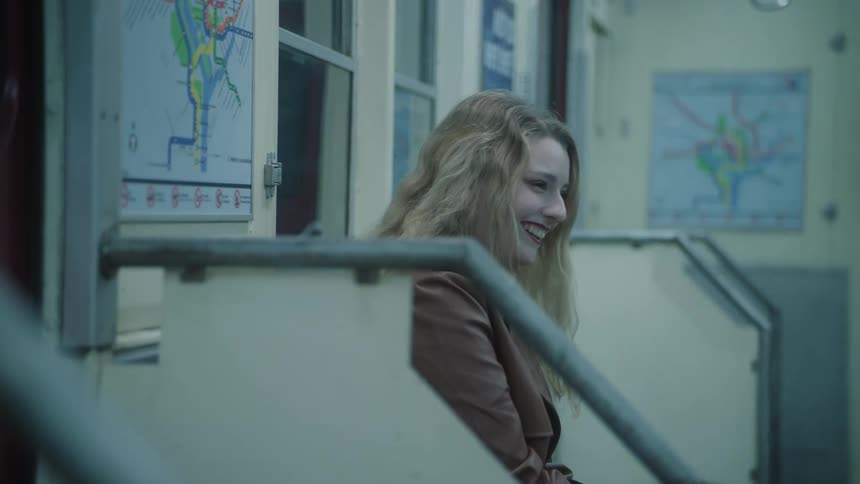 Young blonde woman sitting on a bench in a moving train laughing
