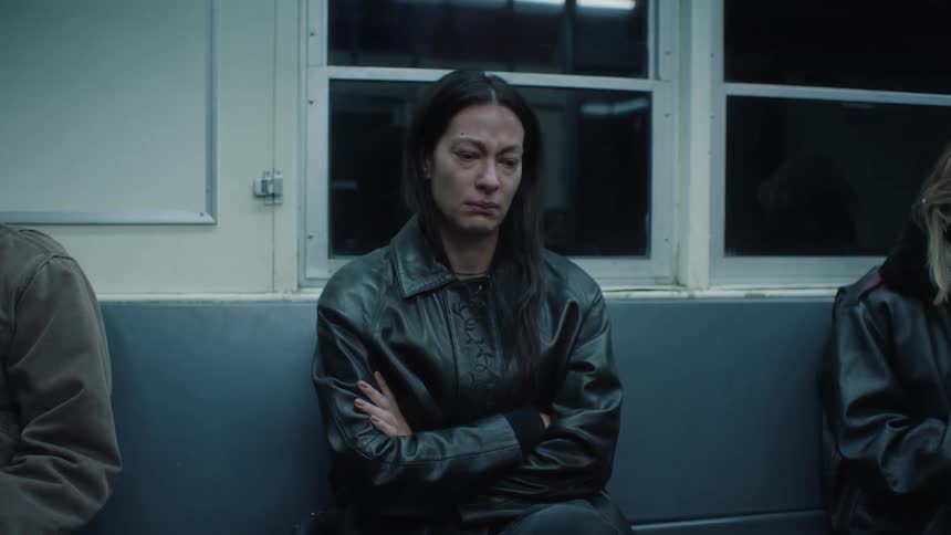 A woman sitting on a subway looking sad then she starts to smile