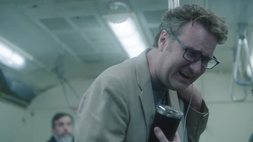 Portrait of a man leaning on a metal rod on a train while laughing