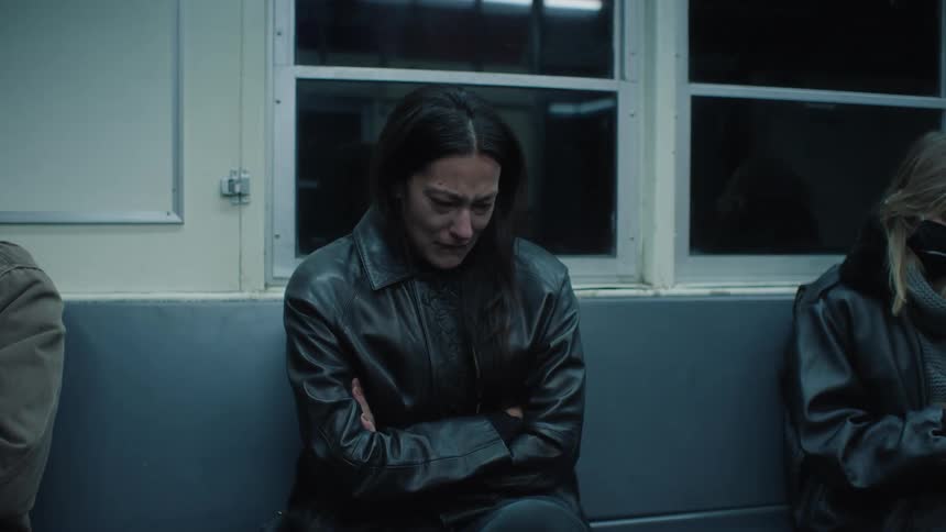 A woman in a dark coat cries indoors
