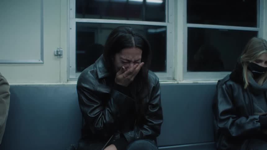 A woman riding a train at night and crying